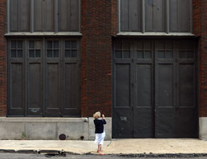 image of woman in black top and white skirt standing in front of a large building with big black doors