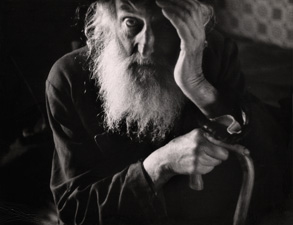 black and white portrait of older man with a white beard and hand against his face