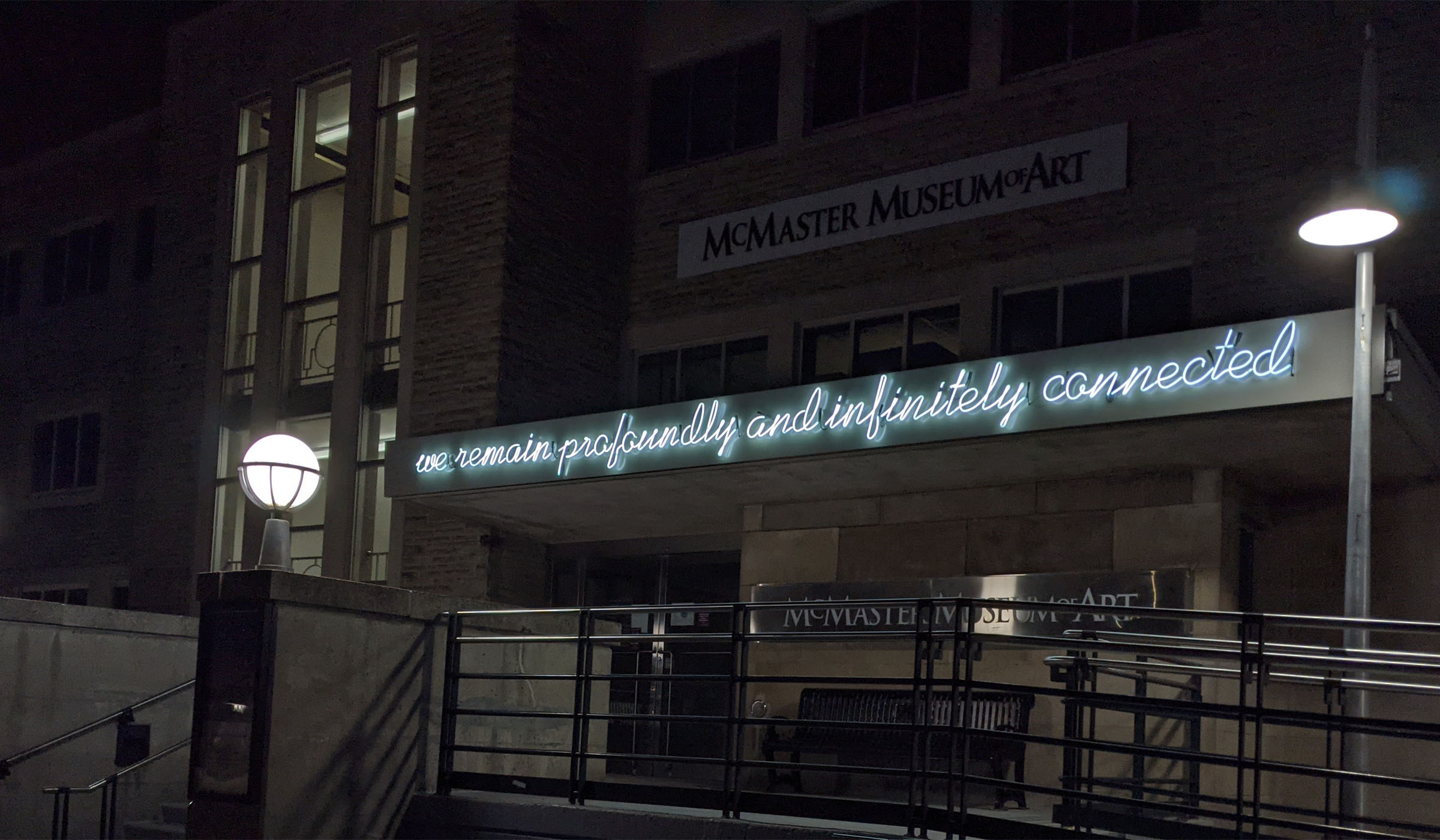 Neon sculpture that reads 'we remain profoundly and infinitely connected' on the facade of the museum
