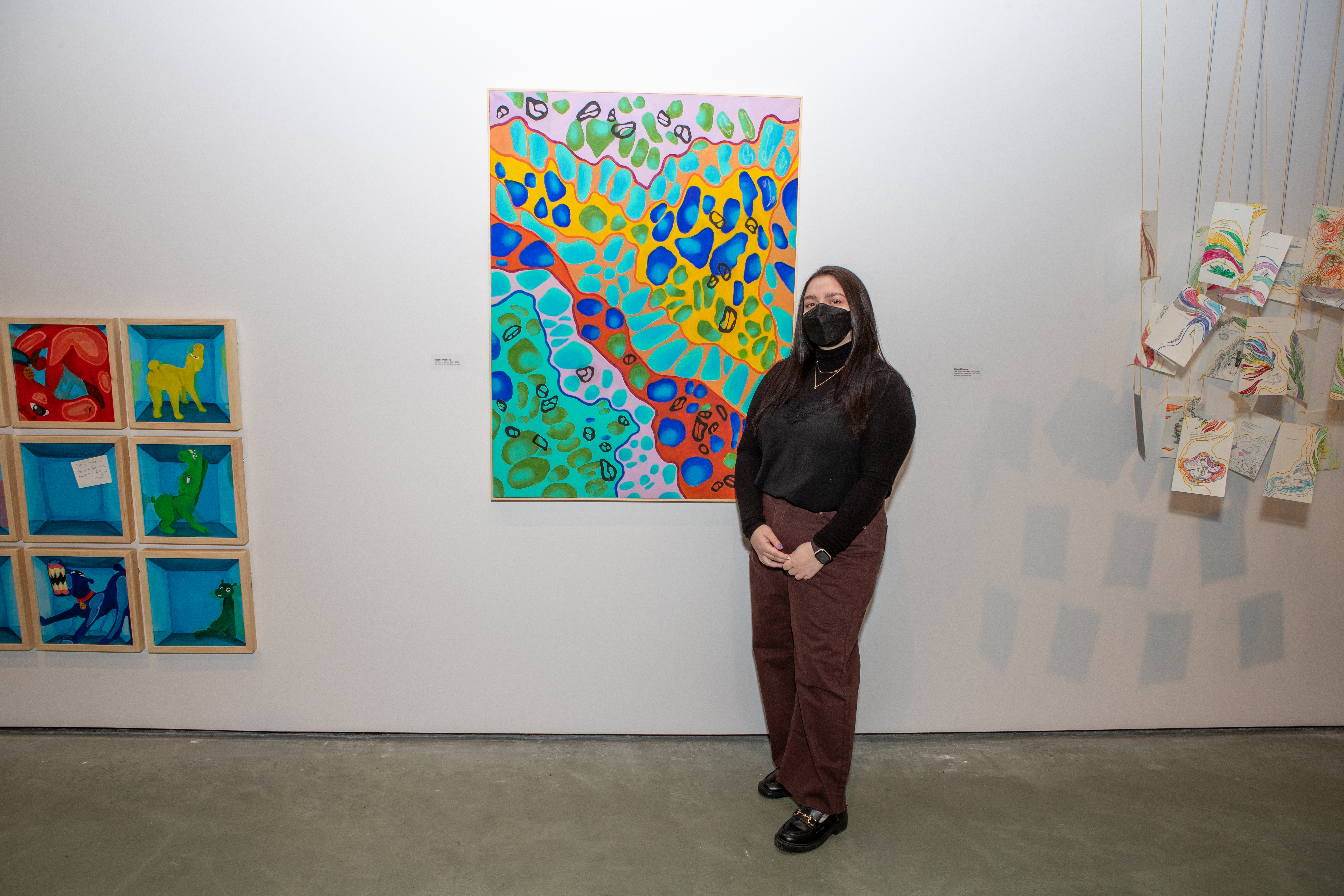 A student in front of an abstract brightly coloured painting