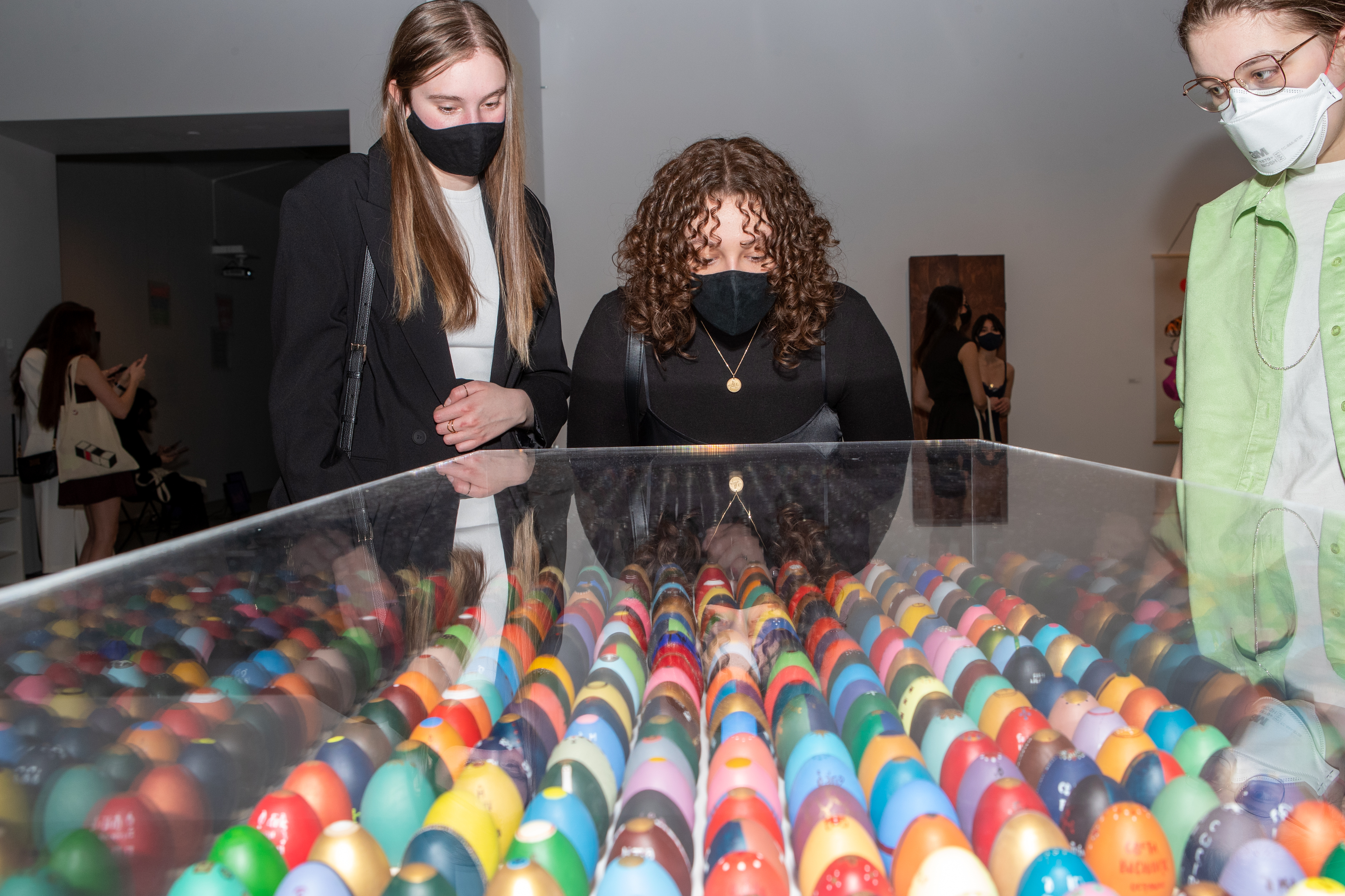 Students looking down at a table of colourful painted eggs