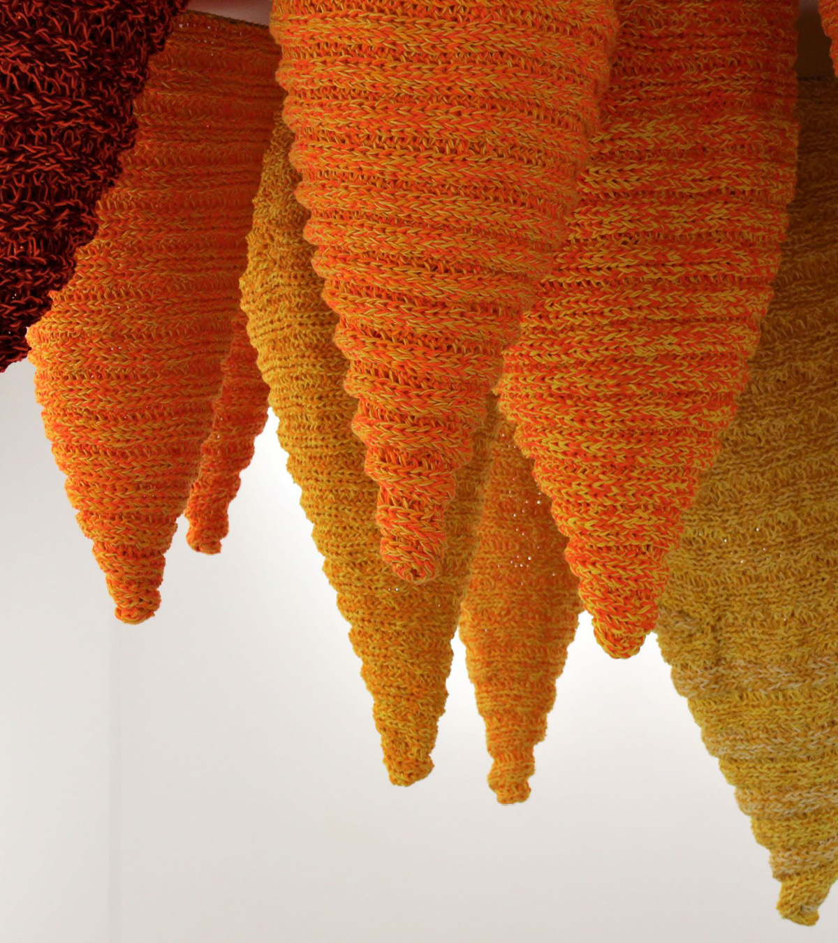 Artwork by Katrina Coomb. Suspended red, orange, yellow finger knitted mixed fibres in the shape of stalagmites.